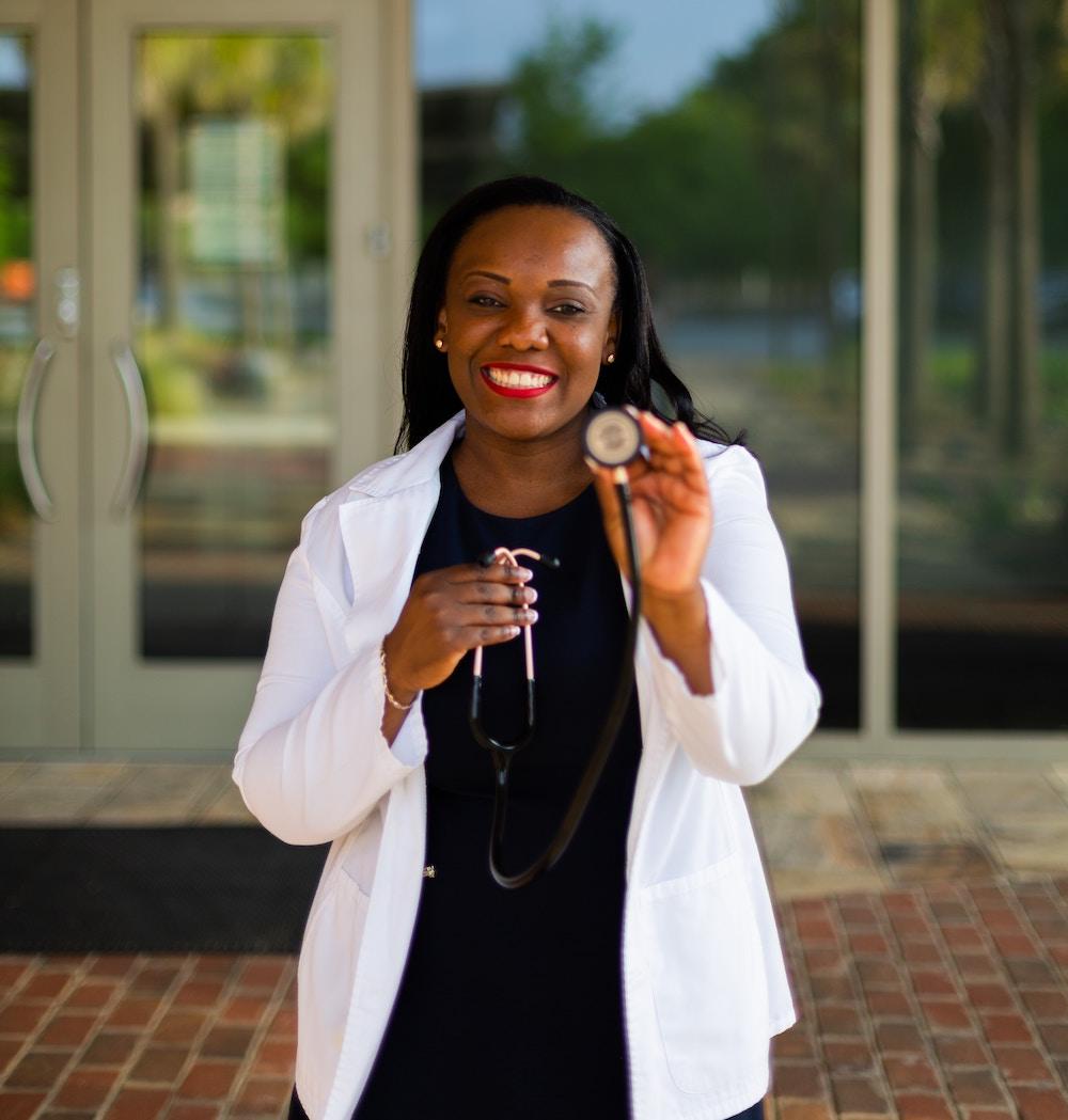 medical professional holding stethoscope and smiling: credit to eben-kassaye-Z7TAIOQgjWA-unsplash"